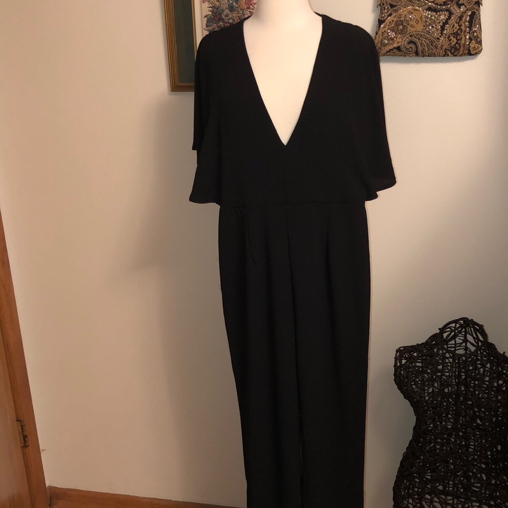 Black jumpsuit with cape sleeves, open draped back
